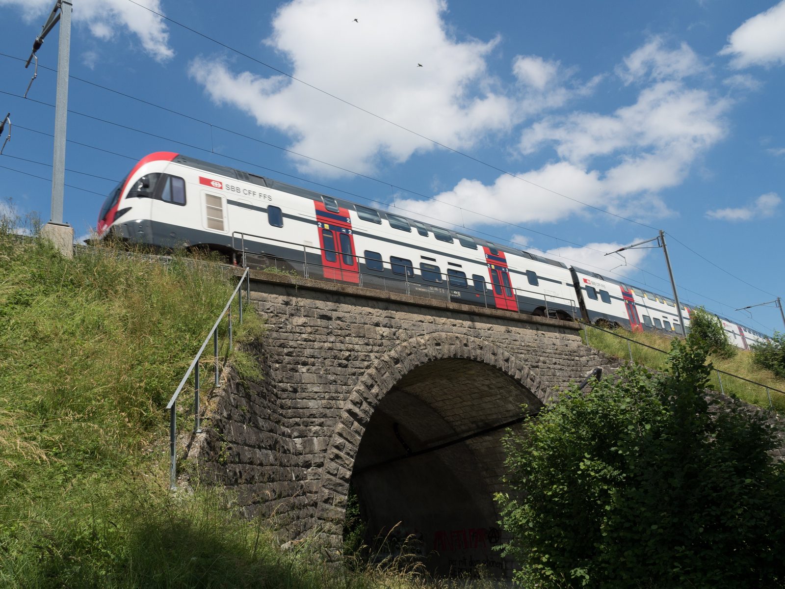 Ein Doppelstockzug der SBB fährt über die steinerne Eisenbahnbrücke über die Murg bei Sirnach